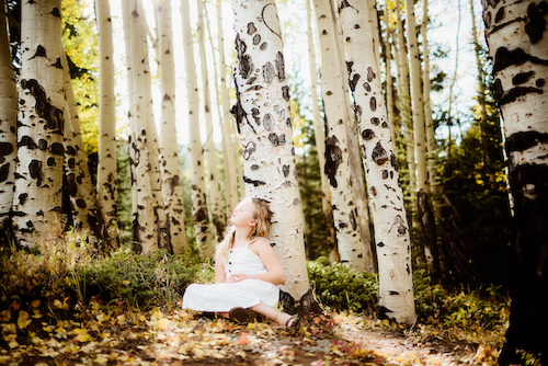 Girl resting against aspen tree
